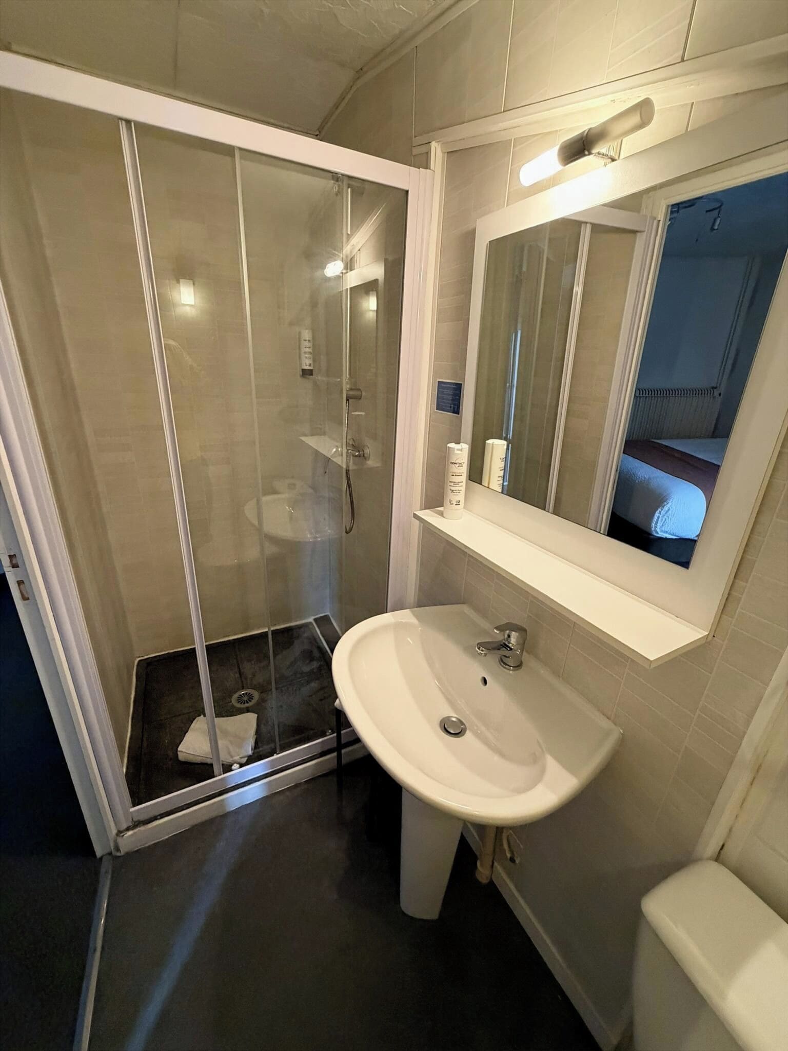 Un baño moderno con ducha de vidrio, un lavabo blanco y un espejo encima.