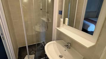 Un baño moderno con ducha de vidrio, un lavabo blanco y un espejo encima.