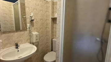 A bathroom with a pedestal sink, toilet, and a glass-enclosed shower area.