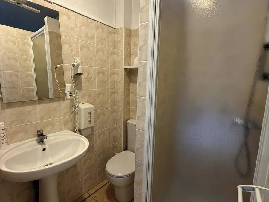 A bathroom with a pedestal sink, toilet, and a glass-enclosed shower area.