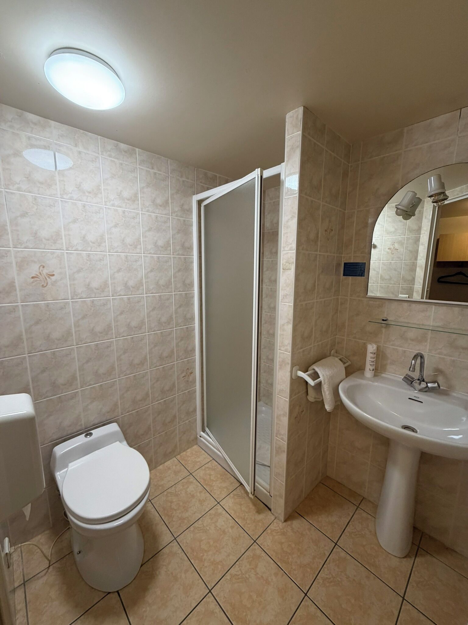 A bathroom with a toilet, a sink, and a shower with a glass door.