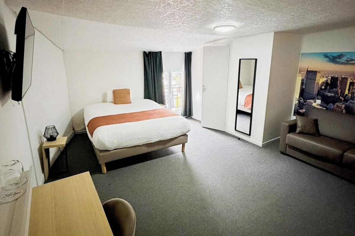 Ein Hotelzimmer mit Bett, Schreibtisch, einer Couch und einem großen Fenster.