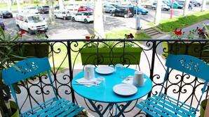A balcony with a blue table set for two, two blue chairs, and a green planter with flowers. -  Contact Hôtel les Platanes Villeneuve sur Lot Centre (Villeneuve-sur-Lot)