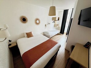 A hotel room with two beds, a desk, a TV, and a window with curtains. -  Contact Hôtel les Platanes Villeneuve sur Lot Centre (Villeneuve-sur-Lot)