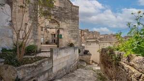 A narrow stone pathway leading to a building with a traditional arched entrance. - La Corte Vetere (Matera)