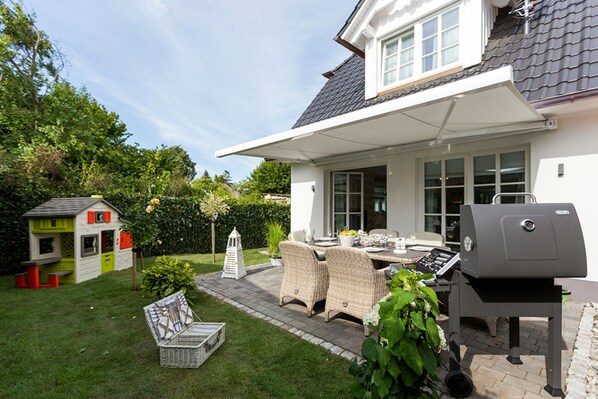 A patio with outdoor furniture, a barbecue grill, and a children's playhouse.