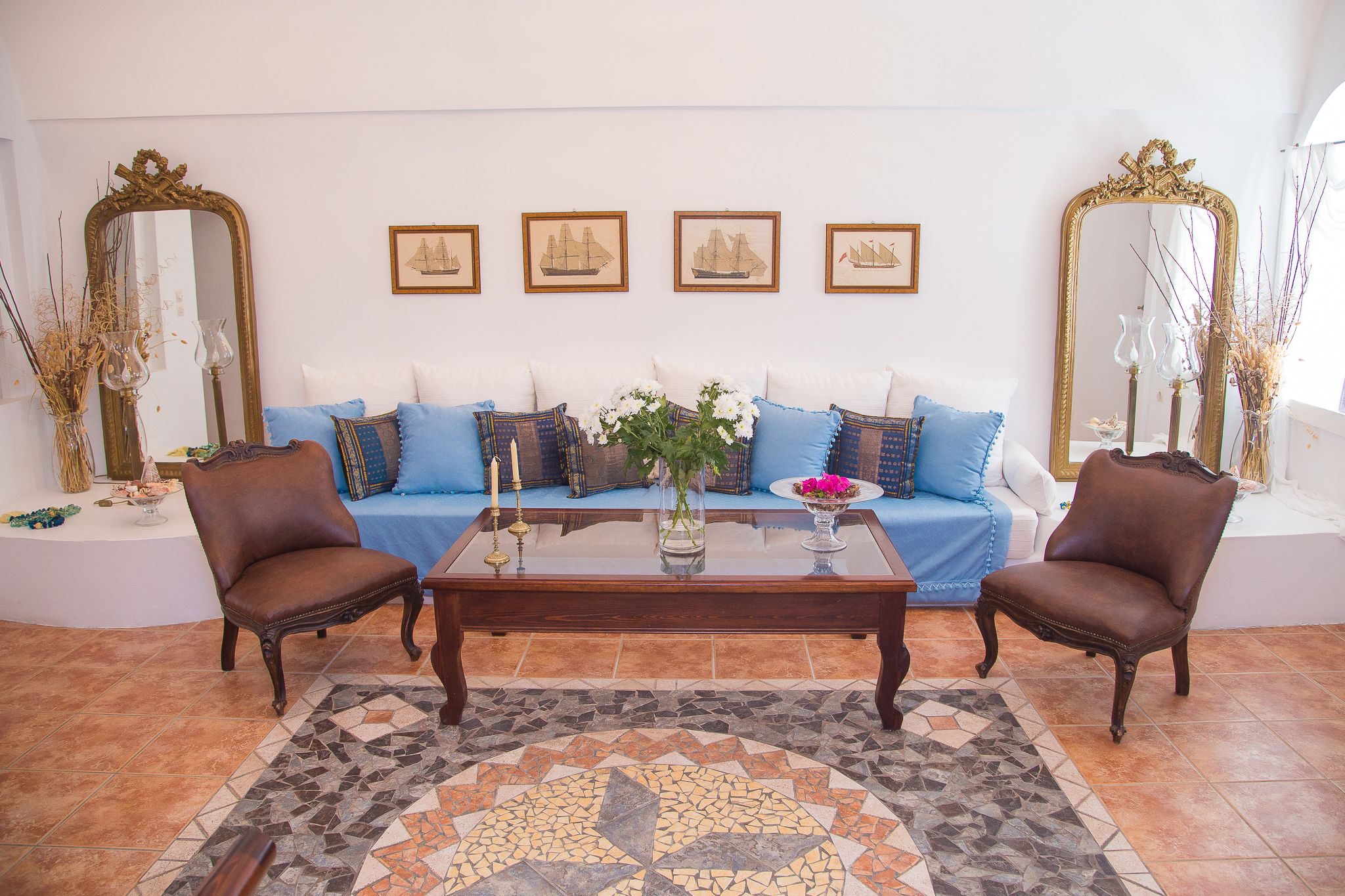 Uma sala de estar com sofá, duas poltronas, uma mesa de centro e objetos decorativos.