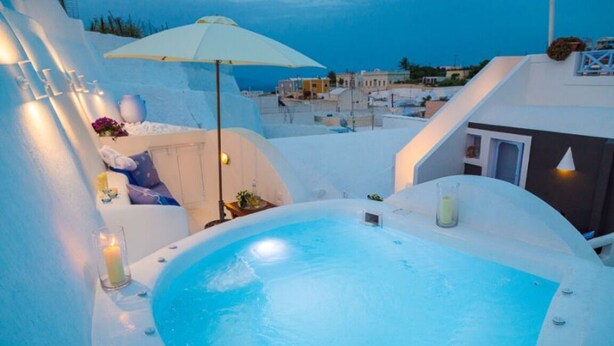 Una piscina en la azotea con una sombrilla blanca, velas y vistas a la ciudad.
