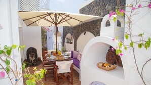 Un espacio comedor al aire libre acogedor, con mesa, sillas y un paraguas grande.