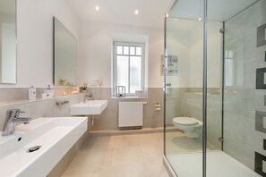 A modern bathroom with a large sink, a mirror, a toilet, and a glass shower enclosure. - Villa Frigga & Villa Freia (Binz)