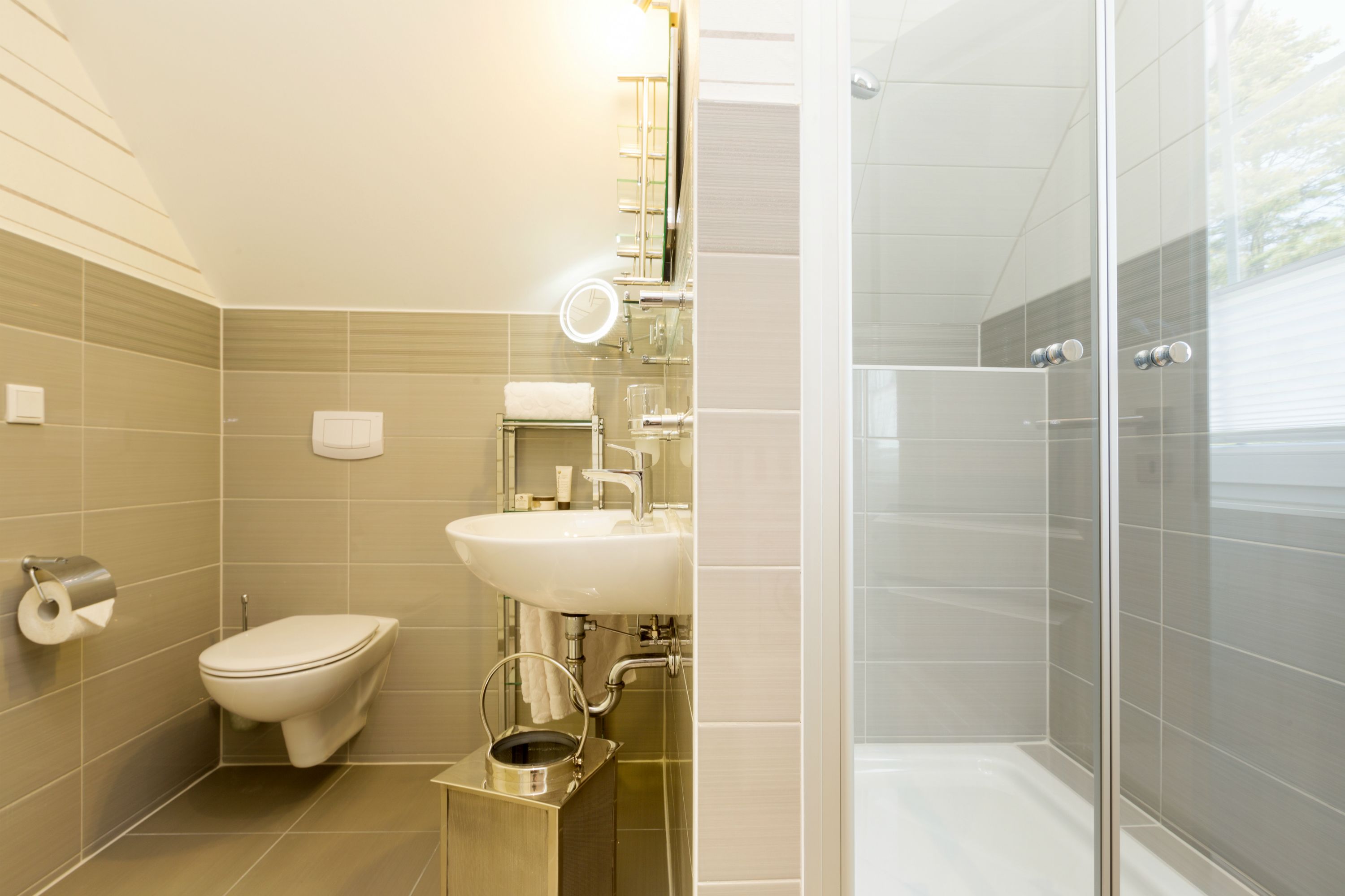 Een moderne badkamer met toilet, wastafel en douchecabine met glazen wanden.