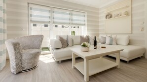 A modern living room with a white sofa, a round armchair, and a coffee table.
