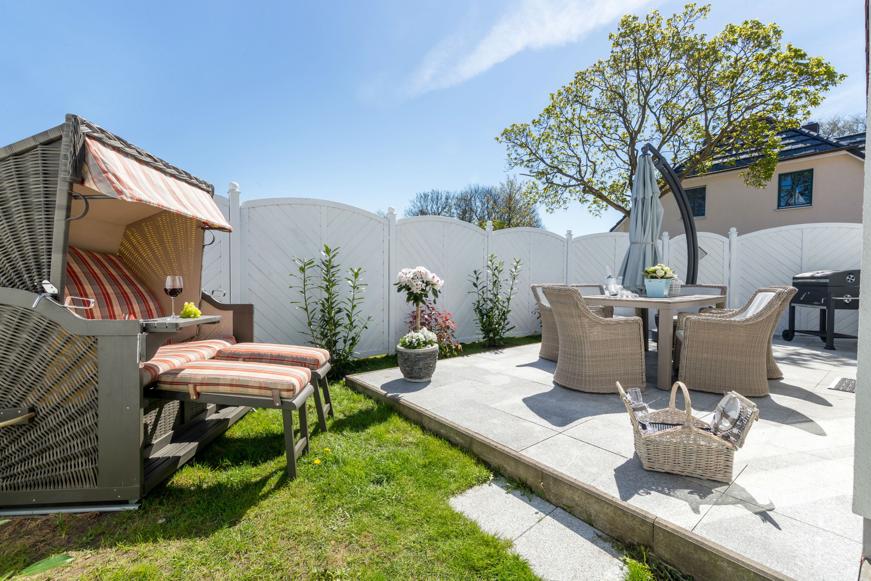 Une terrasse avec des meubles d’extérieur, un barbecue et un petit coin jardin.