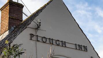 A building with the sign "Plough Inn" on its facade.
