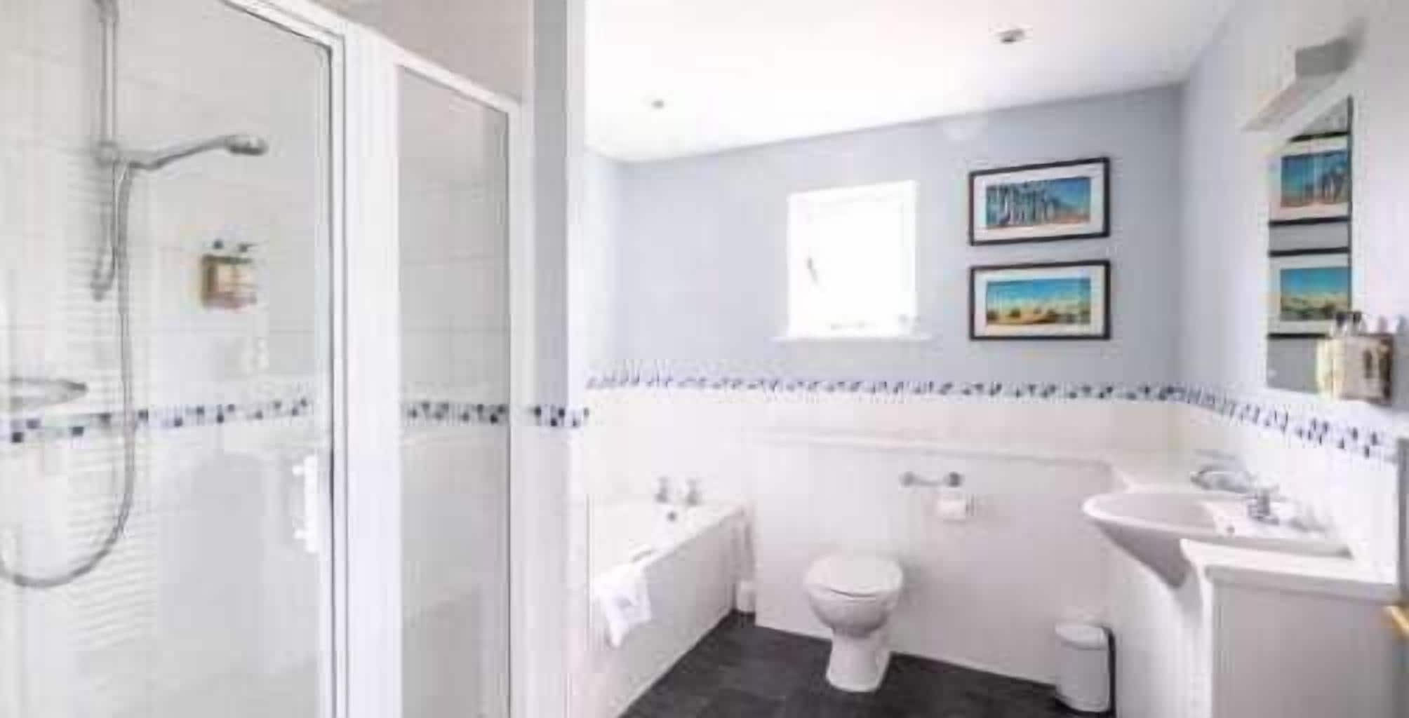 Een moderne badkamer met een douchecabine van glas, een toilet, een wastafel en een klein raam.