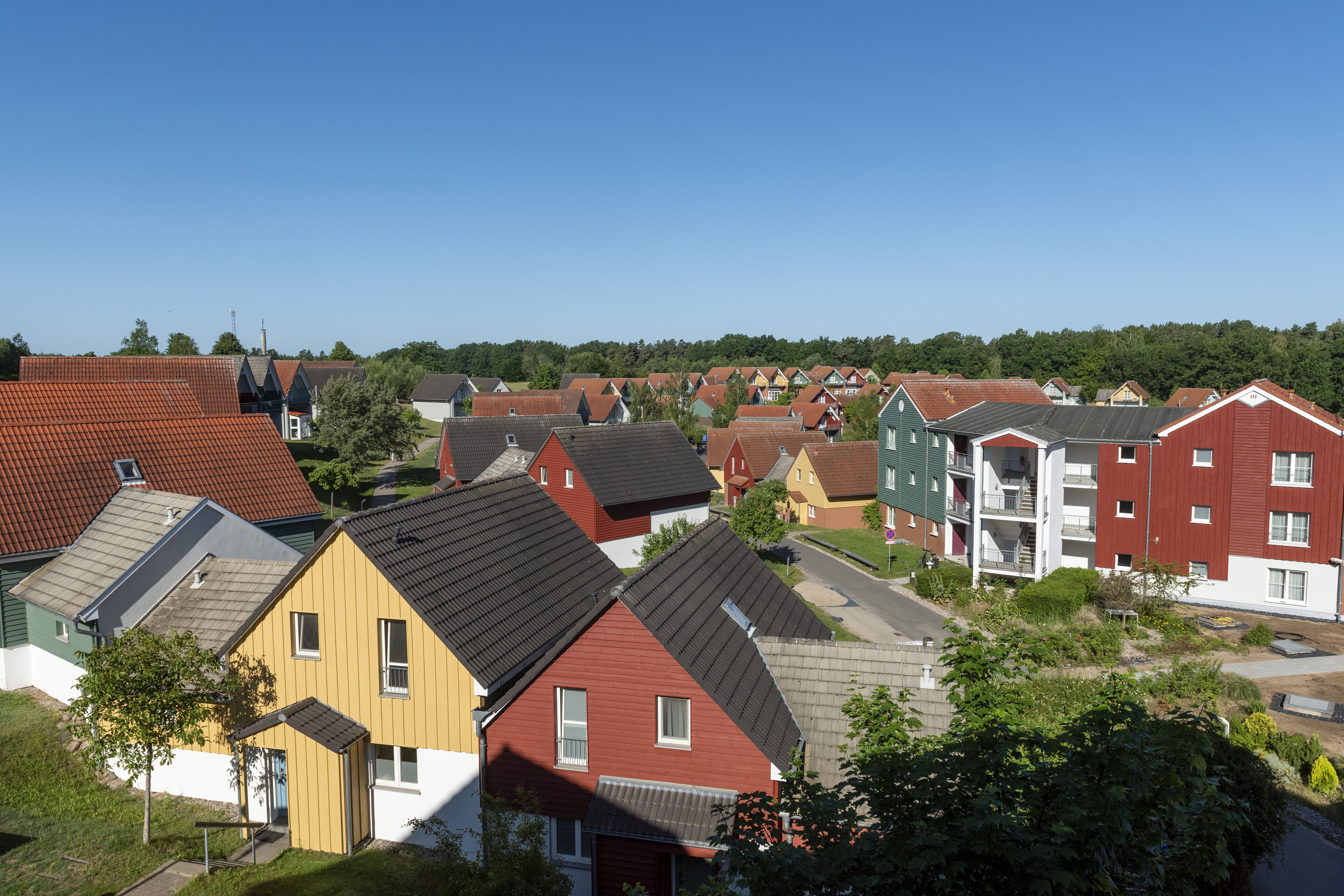 A residential area with various houses and apartment buildings, featuring different roof styles and colors.