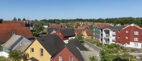 A residential area with various houses and apartment buildings, featuring different roof styles and colors.