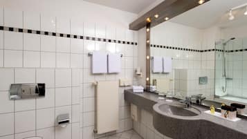 Un bany modern amb un mirall gran, un lavabo de granit i una cabina de dutxa de vidre.