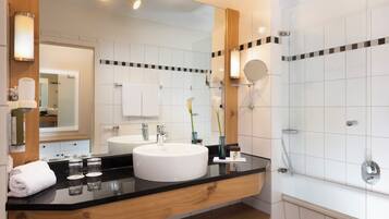 A modern bathroom with a large mirror, two sinks, a bathtub, and a shower.
