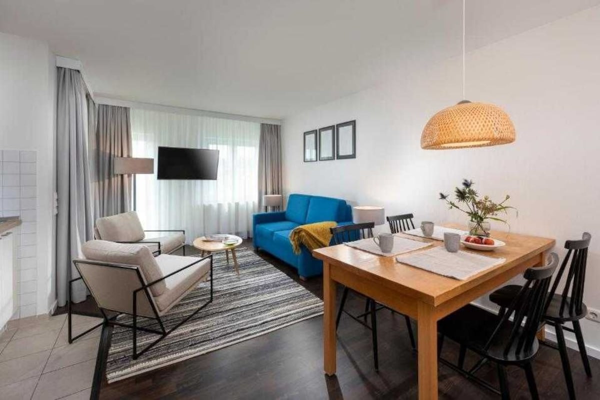 Una sala moderna con sofá, mesa de comedor y televisor.