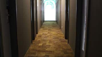 Un pasillo largo y estrecho con un suelo estampado y puertas a ambos lados.