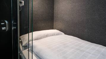A hotel room with a bed, a glass door, and a control panel.