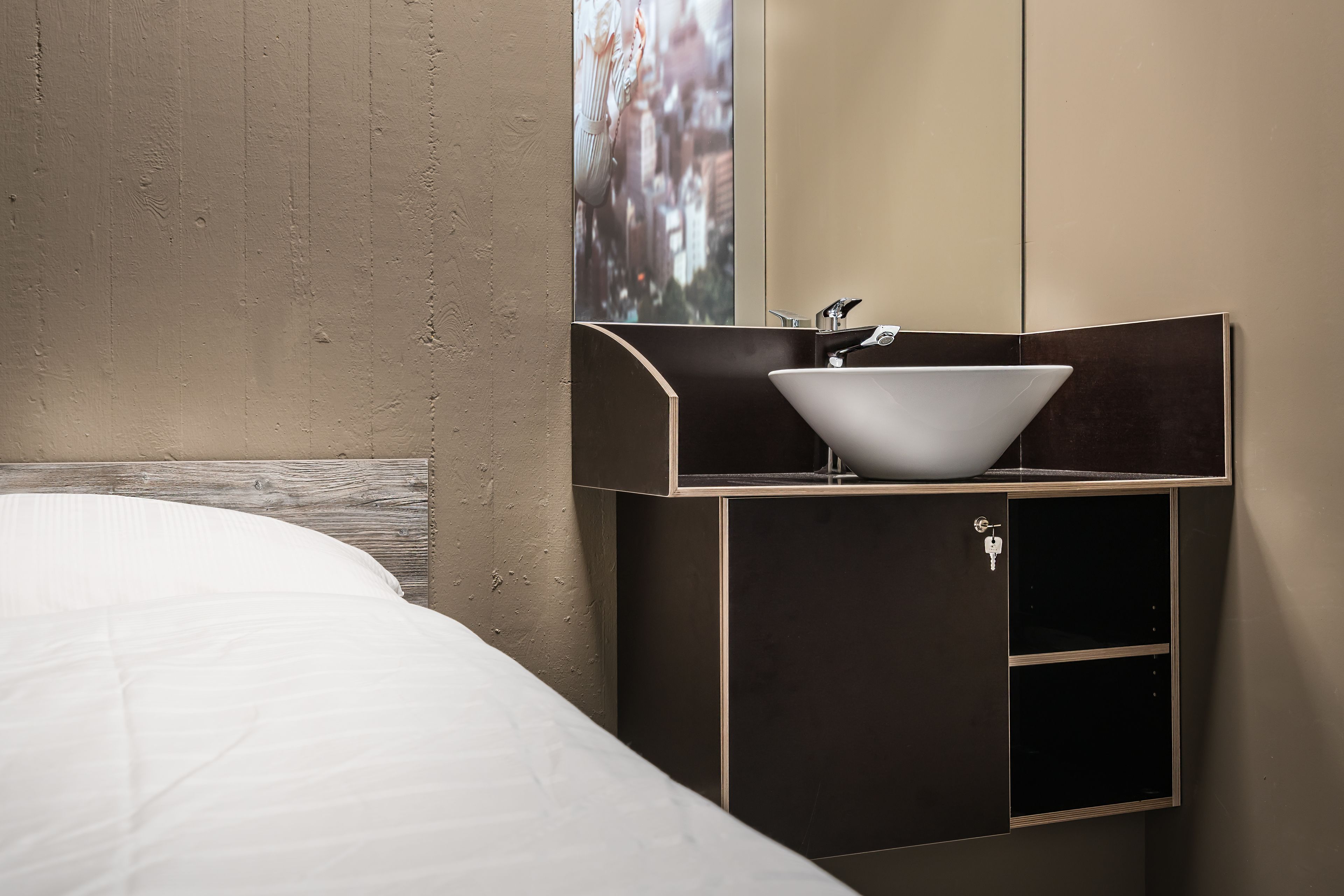 A modern bathroom with a white sink, a mirror, and a wooden headboard.