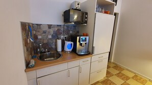 A compact kitchen with a stainless steel sink, a coffee machine, and a microwave.
