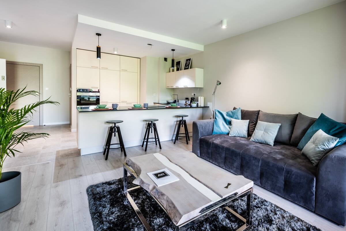 A modern living room with a grey sofa, black stools, and a coffee table.