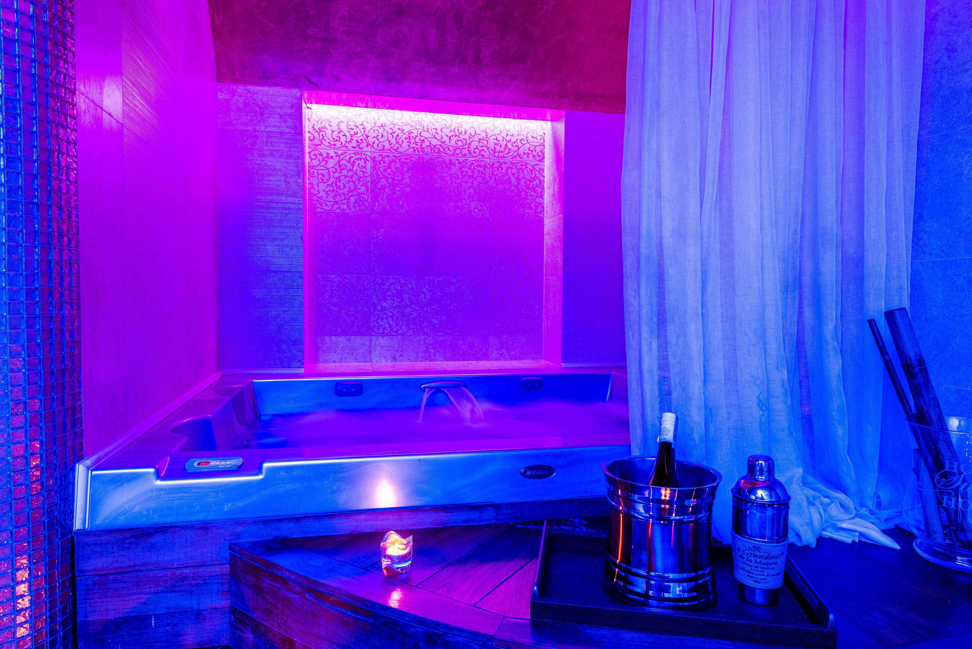 Een wellnessruimte met een jacuzzi, kaarsen en champagneflessen.