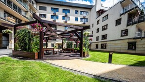 Ein Innenhof mit einer Holz-Pergola, Bänken und Blumenkästen.
