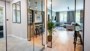 Ein modernes Wohnzimmer mit einer Couch, einem Essbereich mit Hocker und einer Küchenzeile mit Theke und Hockern.