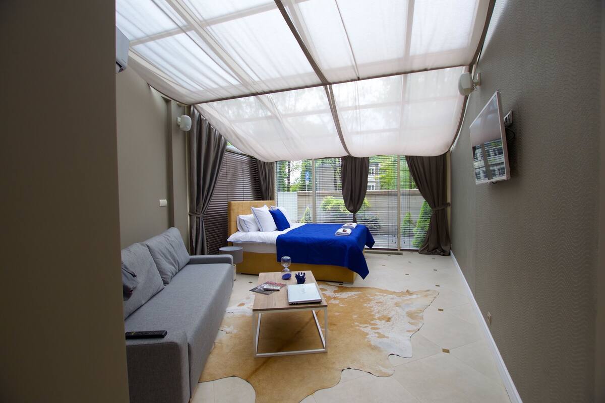 A bedroom with a bed, a sofa, a small table, and a cowhide rug.