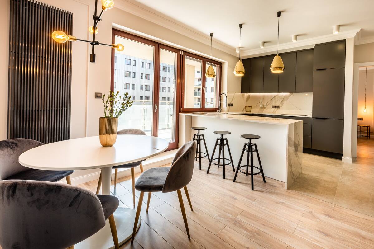 A modern kitchen with a central island, bar stools, and pendant lighting.