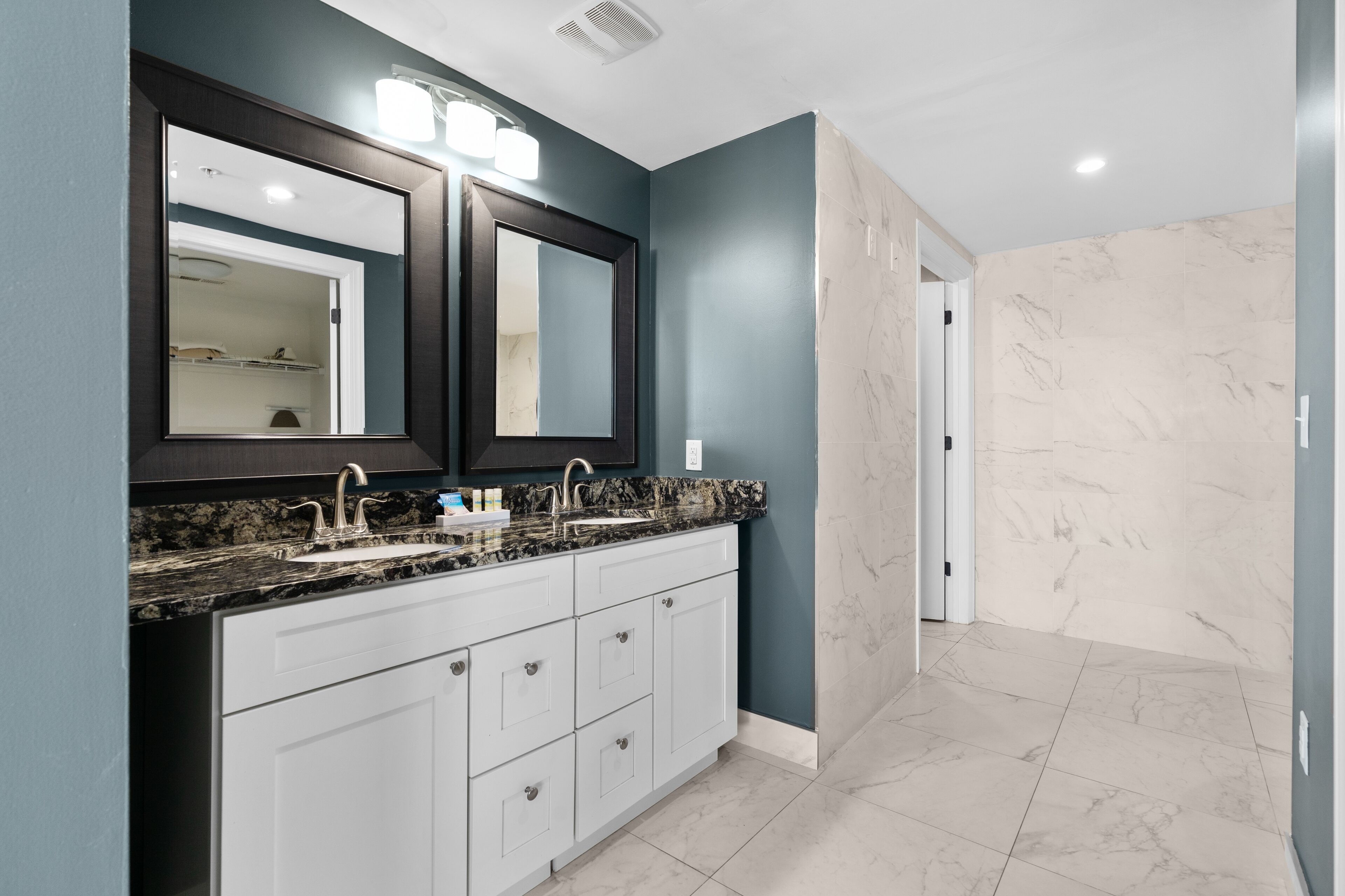 Une salle de bain moderne avec un meuble-lavabo à deux vasques, un revêtement de sol en marbre et un grand miroir.