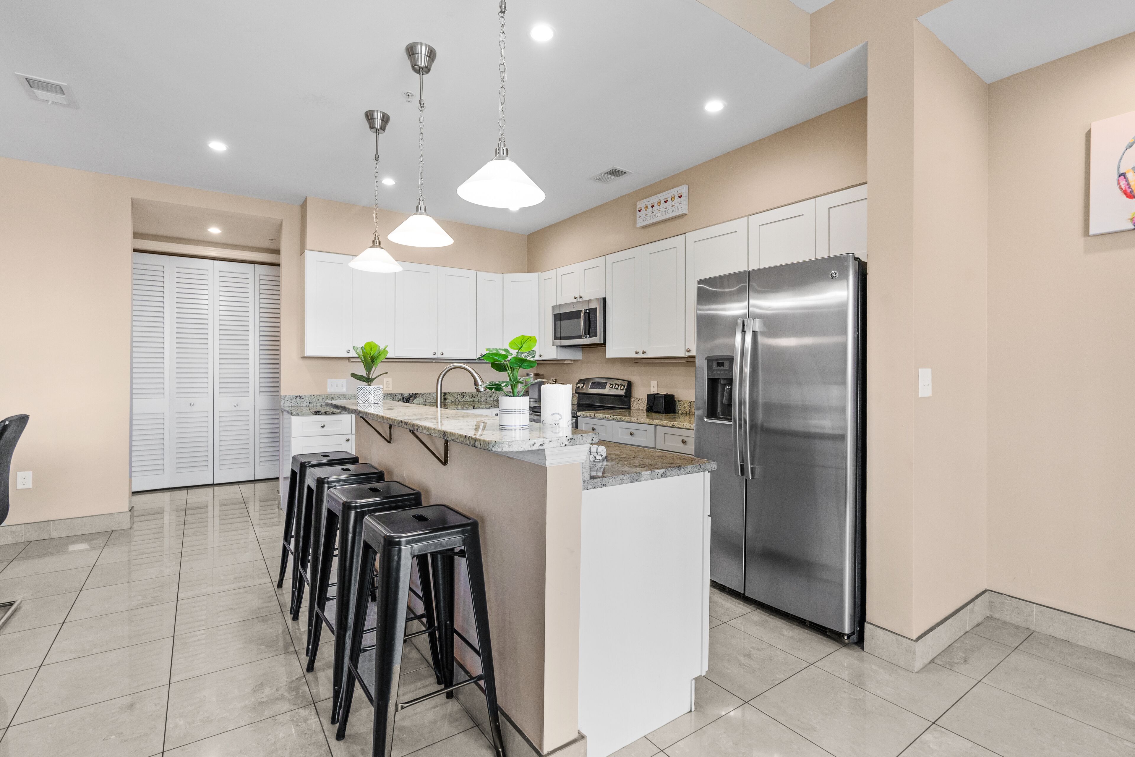 A modern kitchen with white cabinets, stainless steel appliances, and a central island with bar stools.