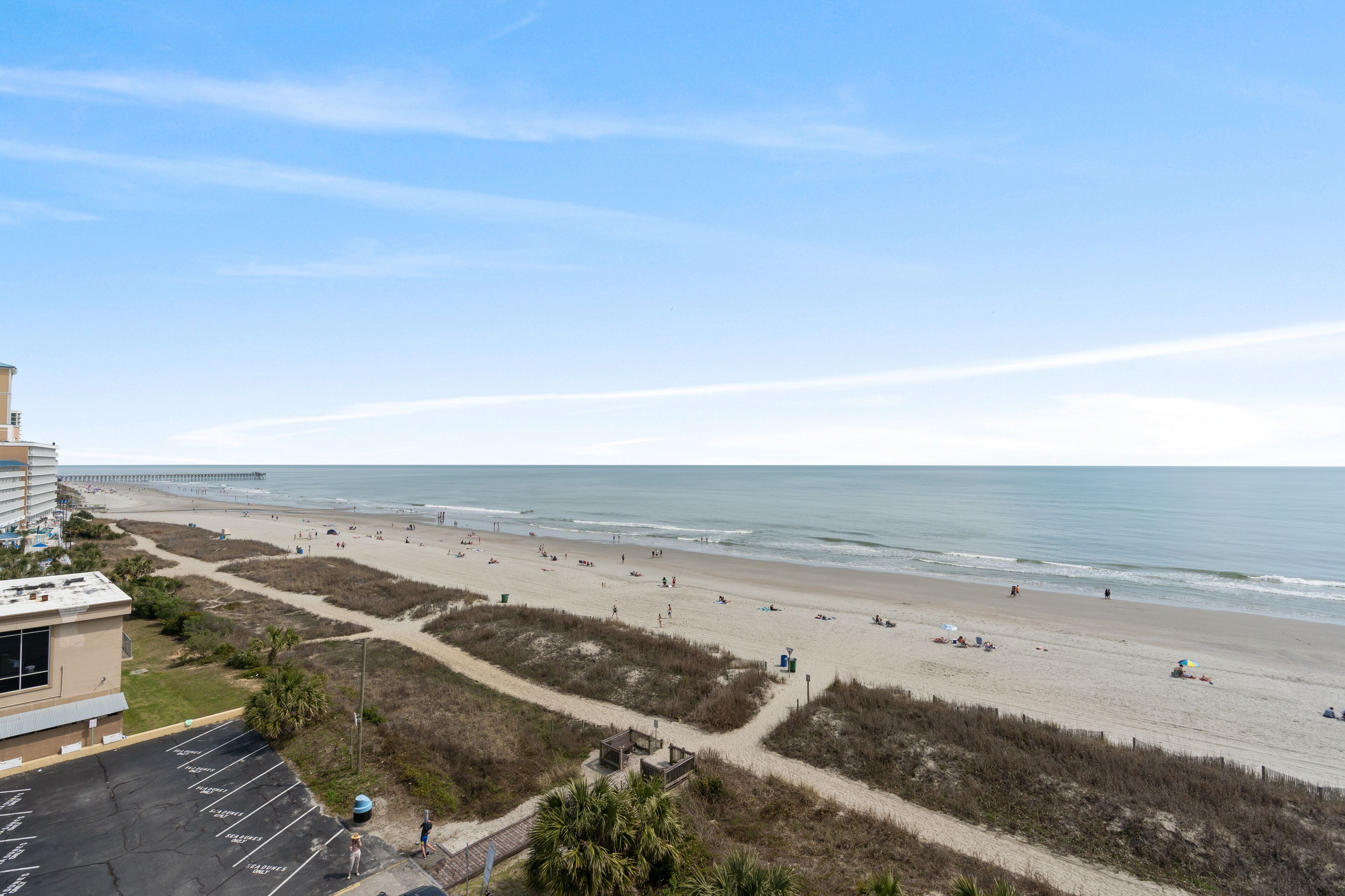 A beach with a parking lot and a building with a flat roof.