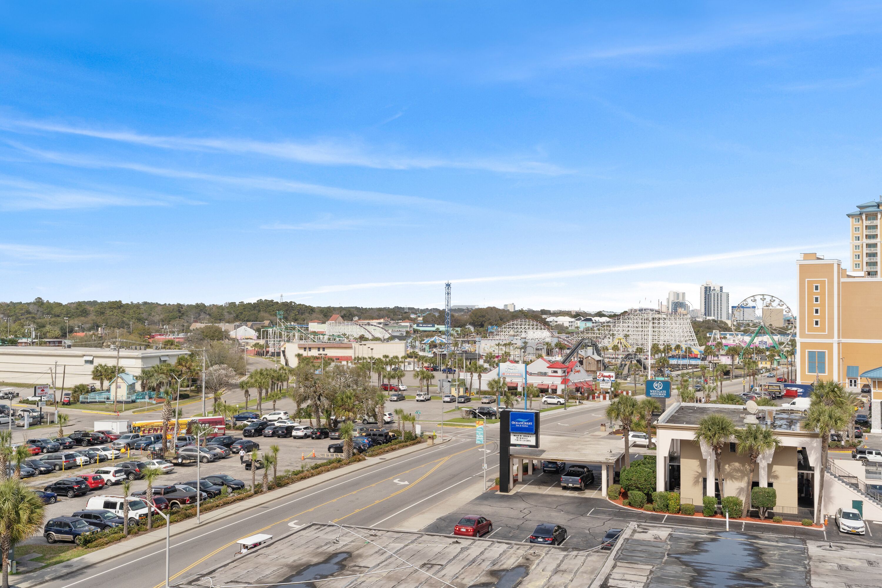 A parking lot with multiple cars, a building with a sign, and a Ferris wheel in the background.