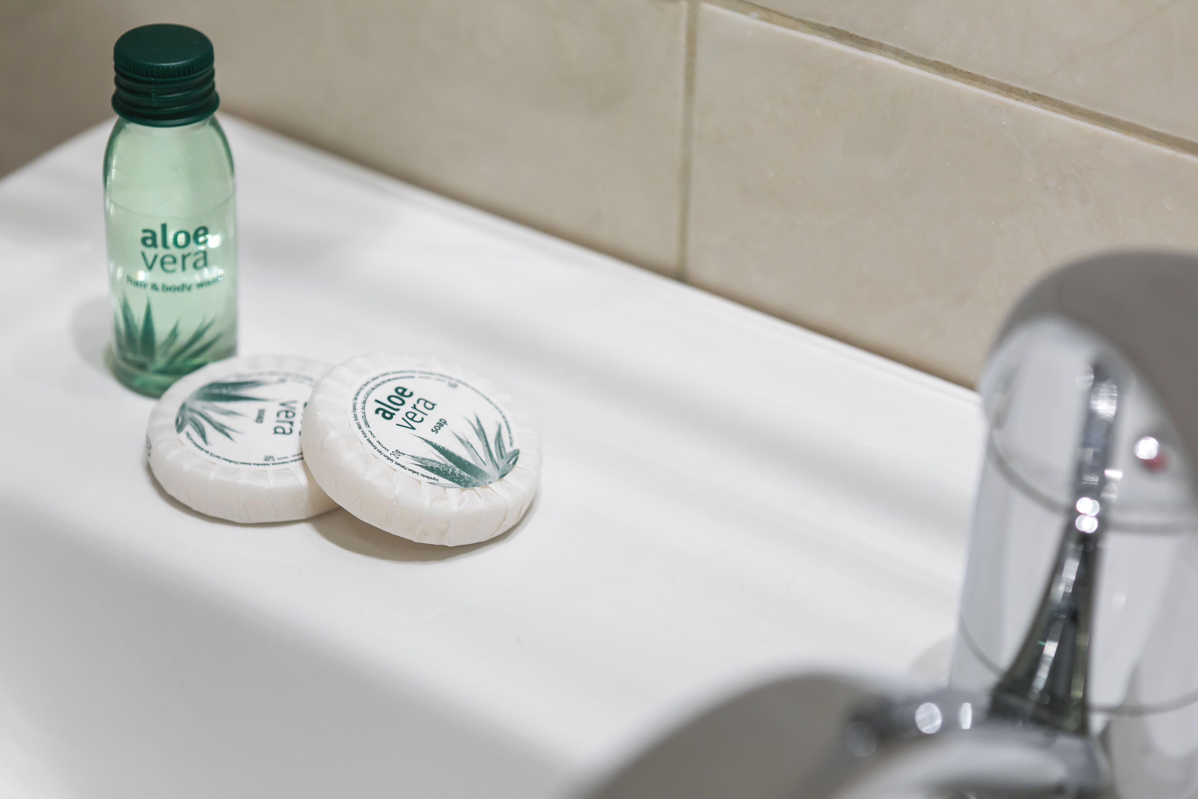 A bathroom sink with a bottle of aloe vera and two soap bars.