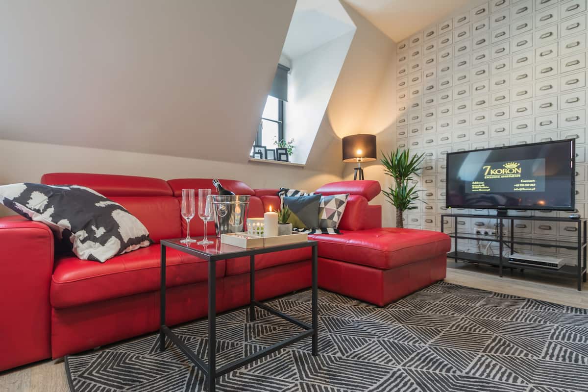 Una sala de estar moderna con un sofá rojo, una mesa de centro de vidrio y un televisor de pantalla plana.