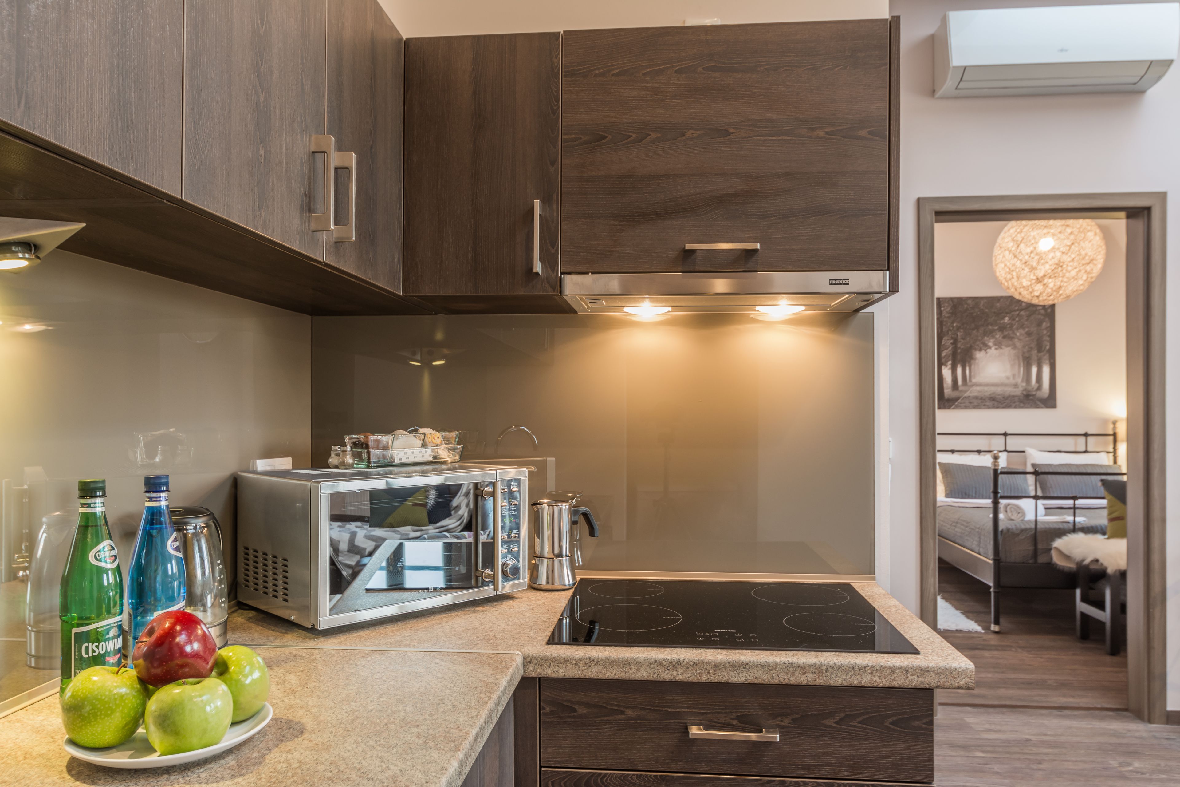 A modern kitchen with dark wood cabinets, a built-in microwave, and a stovetop.