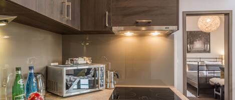 A modern kitchen with dark wood cabinets, a built-in microwave, and a stovetop.