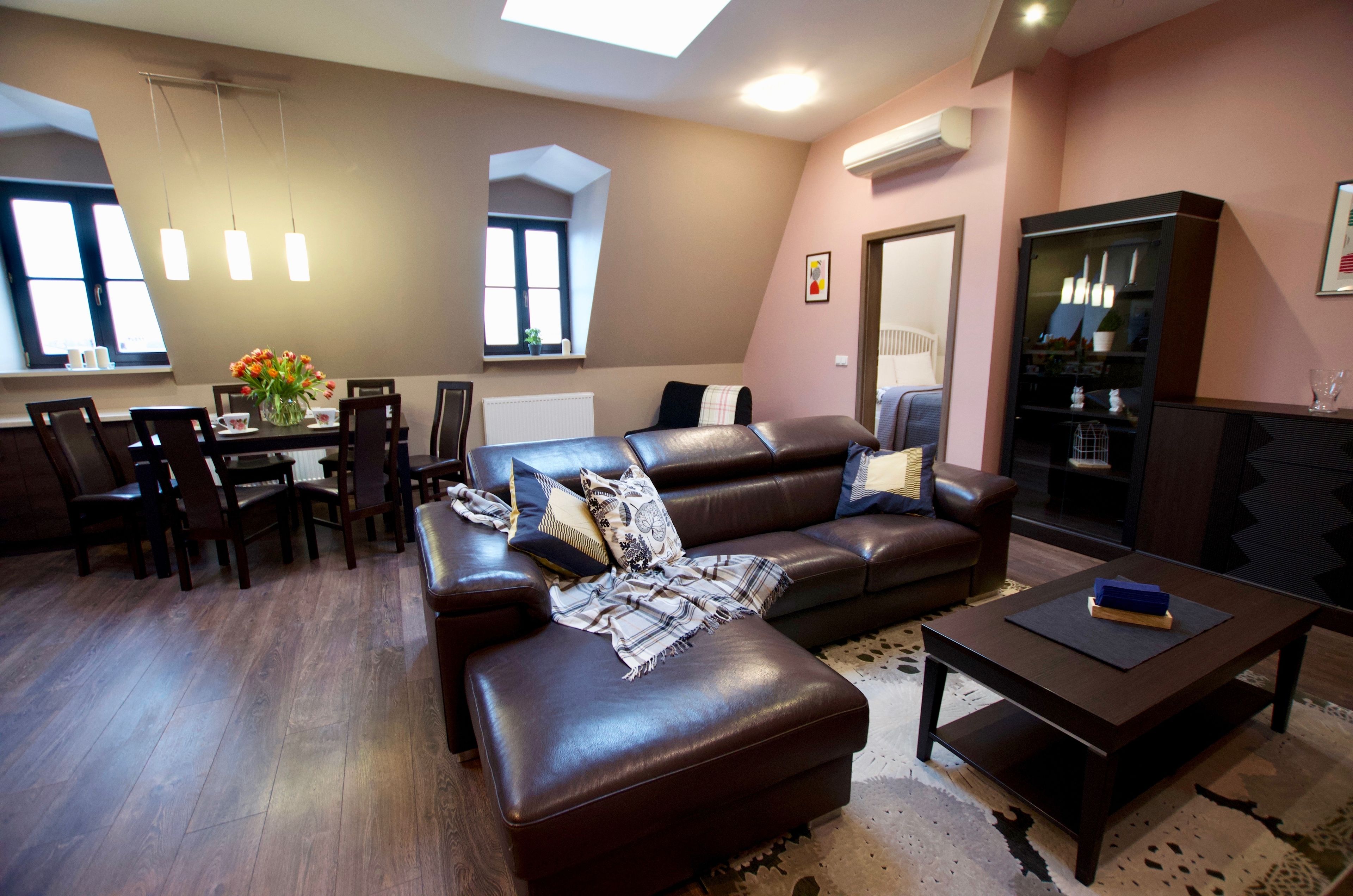 A modern living room with a brown leather sofa, a dining table with chairs, and a coffee table.
