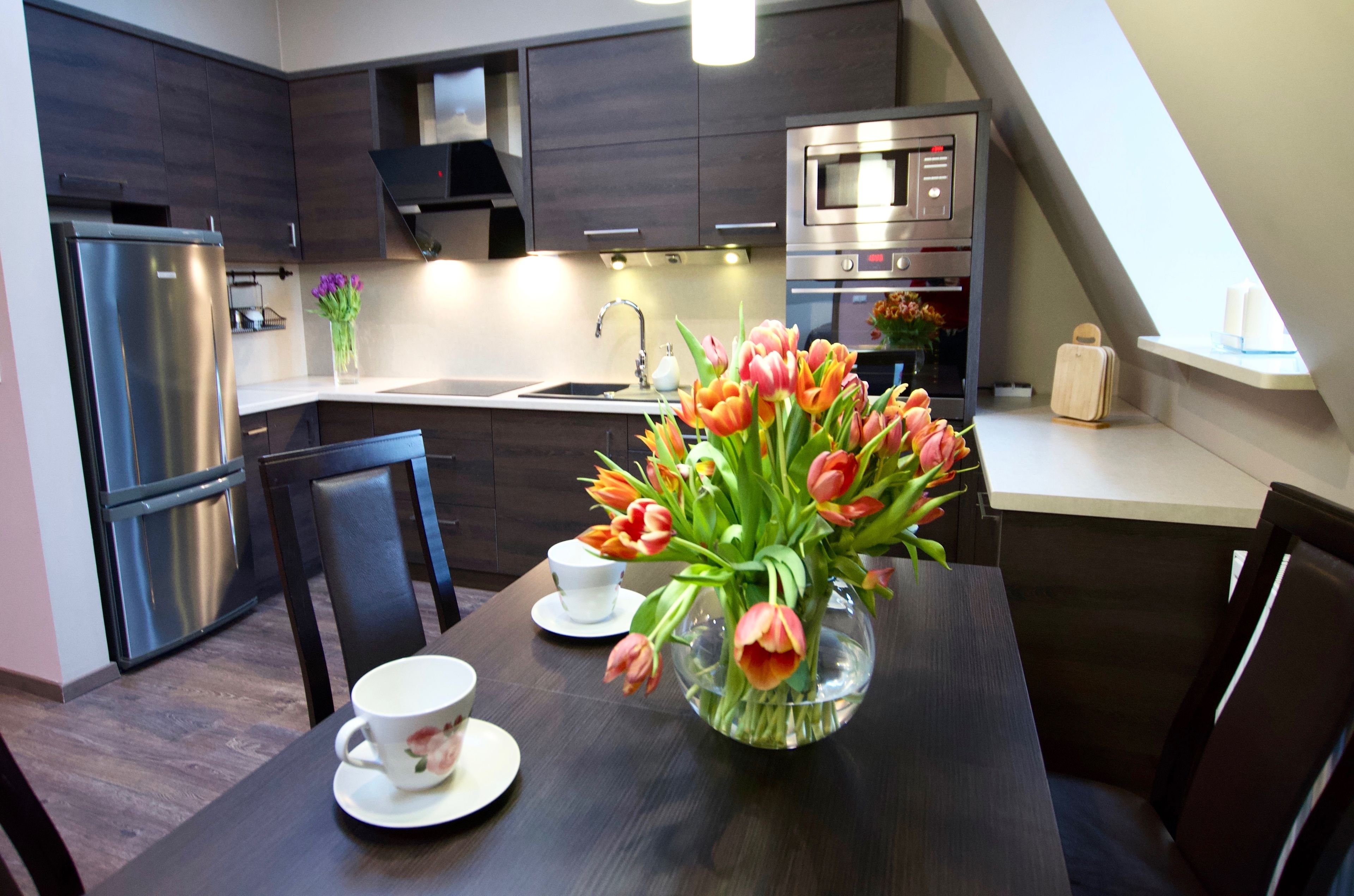 Una cocina moderna con armarios de madera oscura, electrodomésticos de acero inoxidable y un comedor con una mesa para dos.
