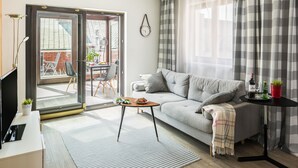 A modern living room with a grey sofa, a small coffee table, and a TV on a stand.