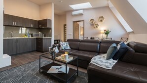 A modern apartment with a kitchen, living area, and a loft bedroom.