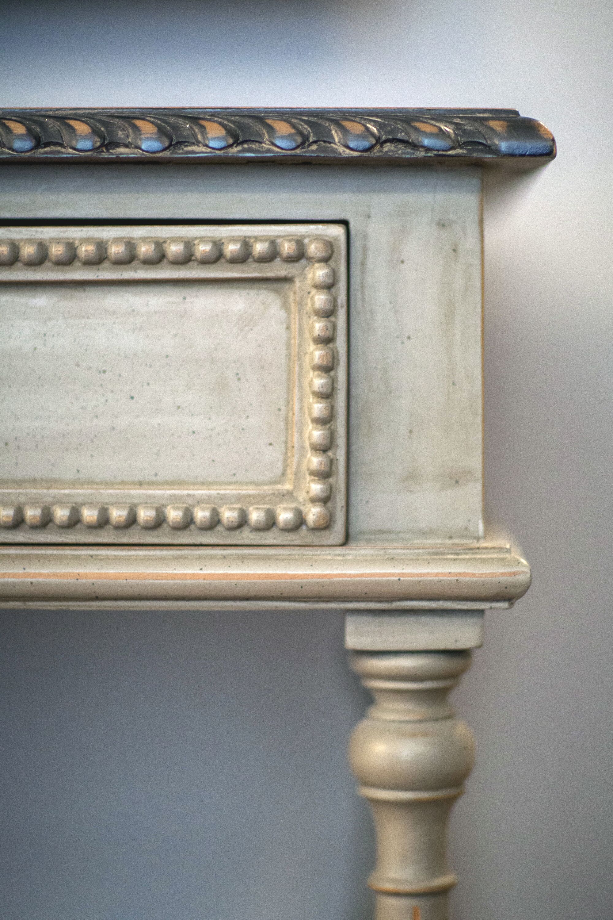 Un gros plan d’une table blanche, richement décorée, avec un plateau orné et un pied tourné.