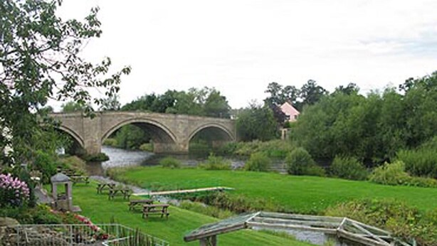 A garden with a stone bridge, picnic tables, and a small pond. - George Hotel (Bishop's Stortford)