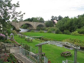A garden with a stone bridge, picnic tables, and a small pond. - George Hotel (Bishop's Stortford)