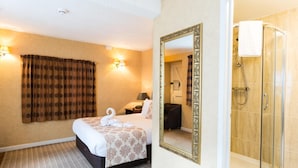 A hotel room with a bed, a shower, a mirror, and a curtain. - George Hotel (Bishop's Stortford)